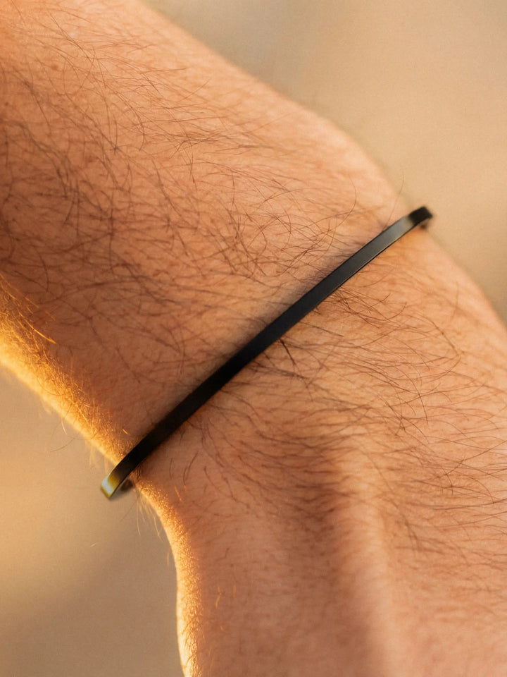 Black bracelet on a person's wrist with a blurred background