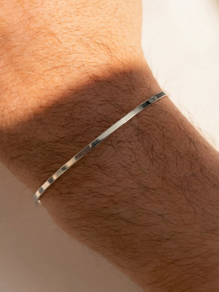 Silver cuff on a person's wrist with a neutral background