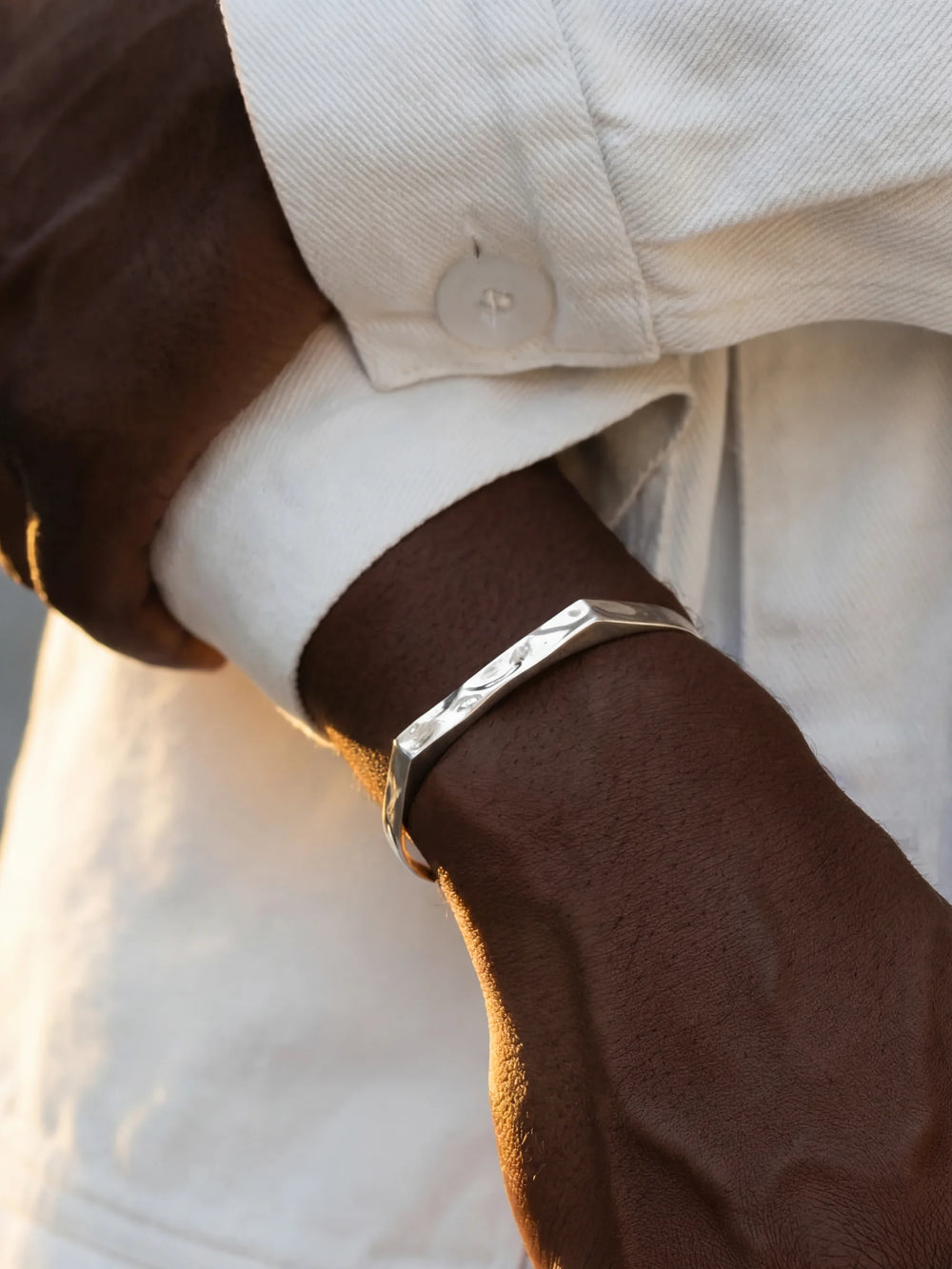 Close-up of a person wearing a silver bracelet with a white shirt
