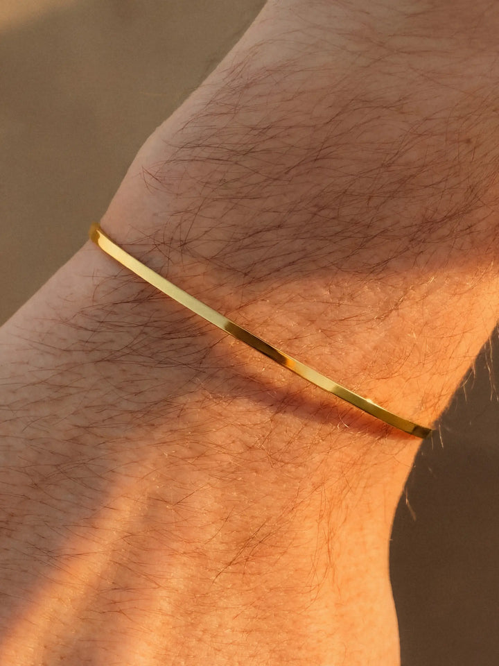 Gold bracelet on a wrist with a blurred background