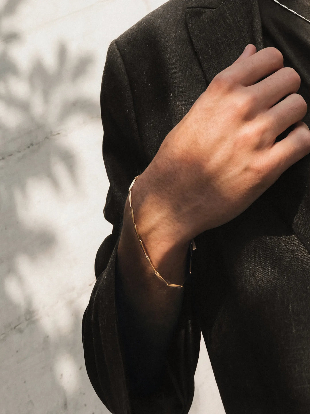 Person wearing a gold bracelet with a dark coat 