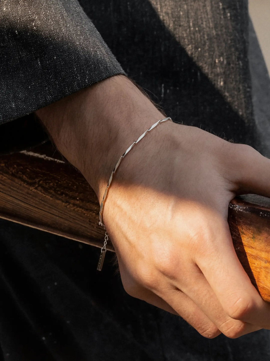 Hand wearing a silver bracelet holding a wooden rail