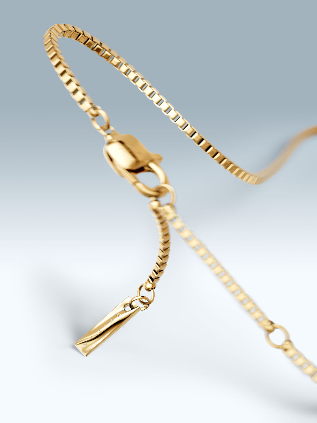 Gold bracelet with a clasp on a light gray background