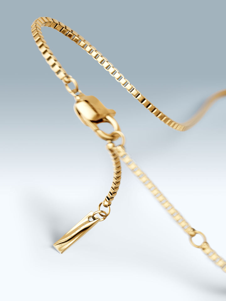 Gold bracelet with a clasp on a light gray background