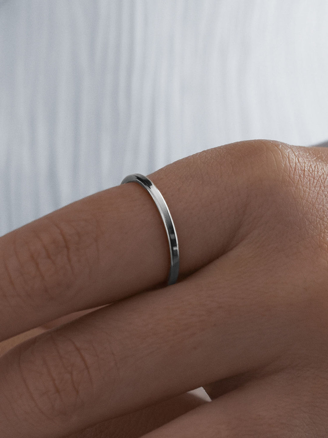 Silver vacier linear ring on a person's finger against a white background