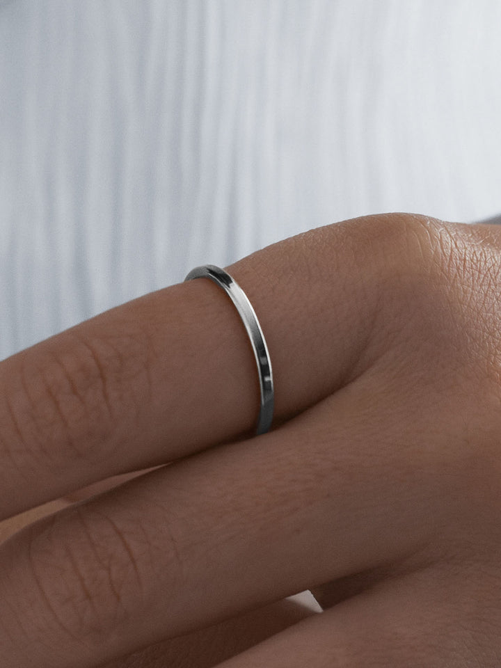 Silver vacier linear ring on a person's finger against a white background