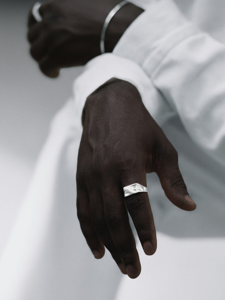 Hand wearing a silver ring on a white background