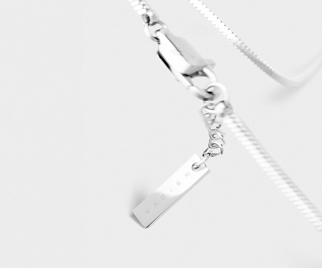 Silver bracelet with a rectangular charm on a light-gray background