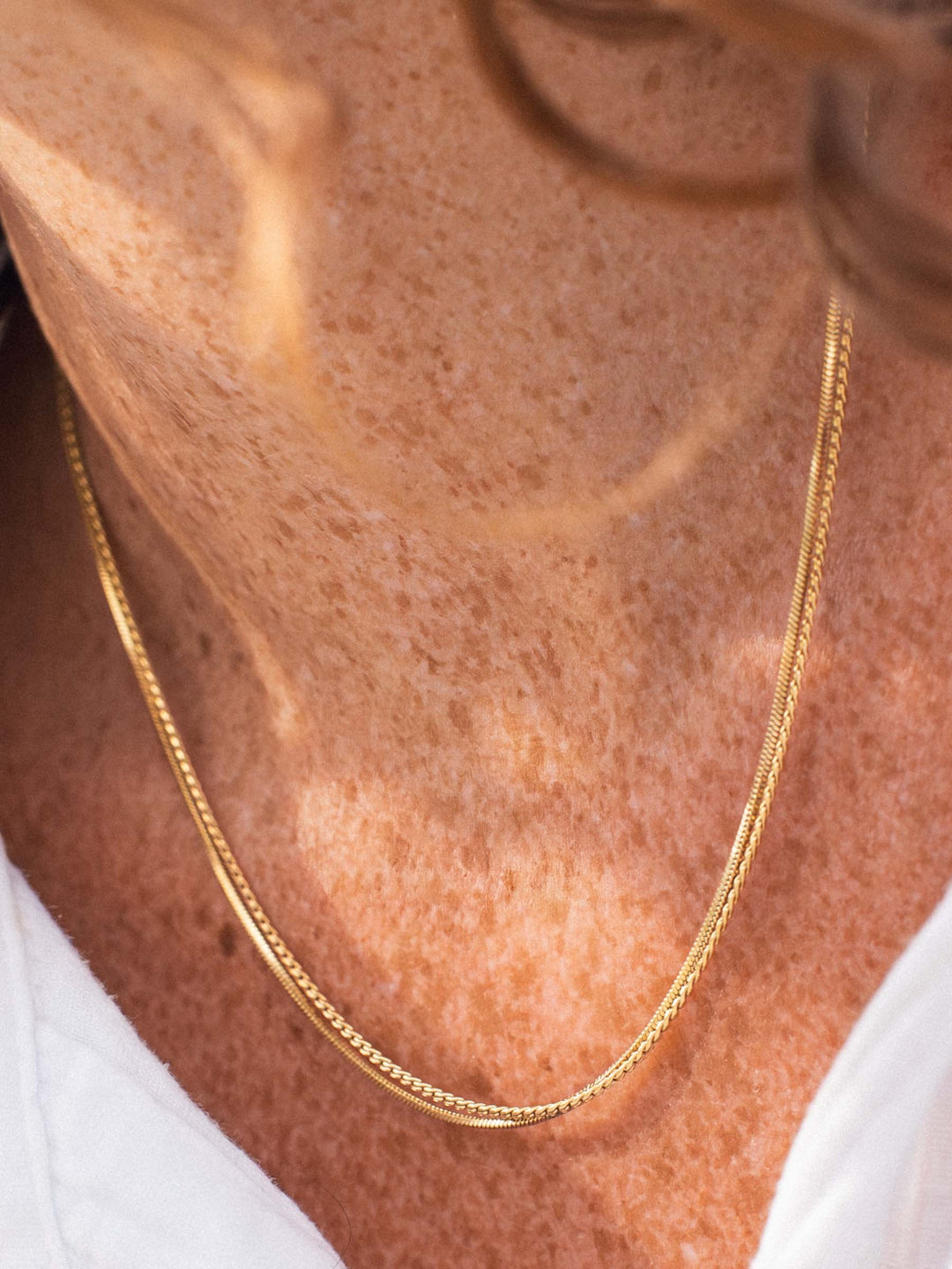 Gold and silver chain necklaces on a person's neck